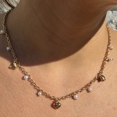 Collier doré à perles blanches pendantes et breloques cœur et papillon porté
