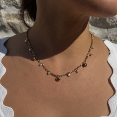 Collier perles blanches pendantes doré porté avec un haut blanc