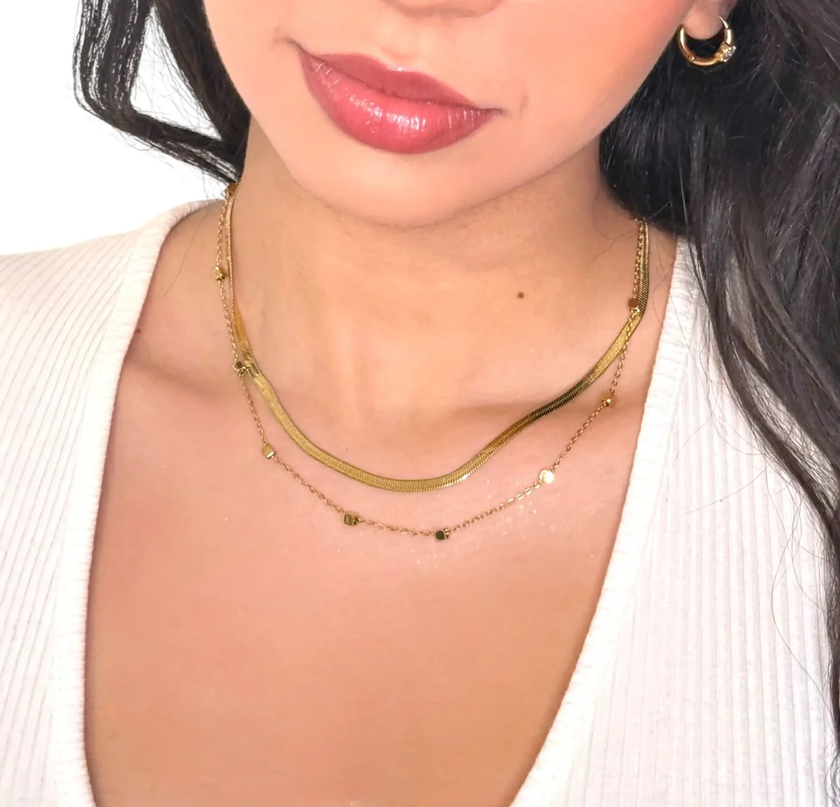a woman wearing a white shirt and gold necklace