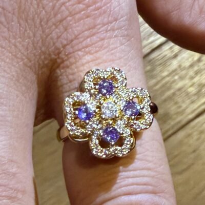 Bague anti stress trèfle violet portée à l'annulaire, métal doré et pierres violettes
