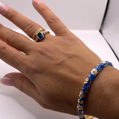 Bracelet jonc en laiton doré émaillé bleu ciel fleurs blanches porté à la main