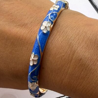 Bracelet jonc émaillé bleu ciel à fleurs blanches porté au poignet