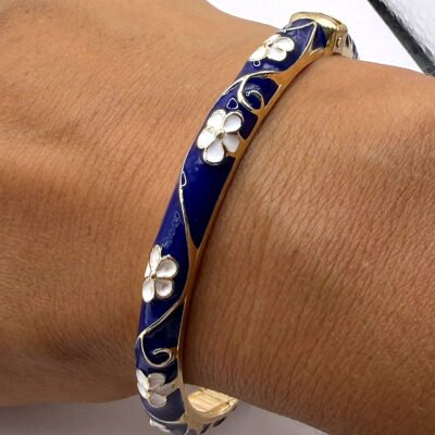 Bracelet jonc émaillé bleu marine à fleurs blanches porté au poignet