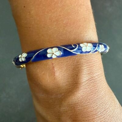 Bracelet jonc émaillé bleu marine au poignet, fleurs blanches en émail et contours dorés