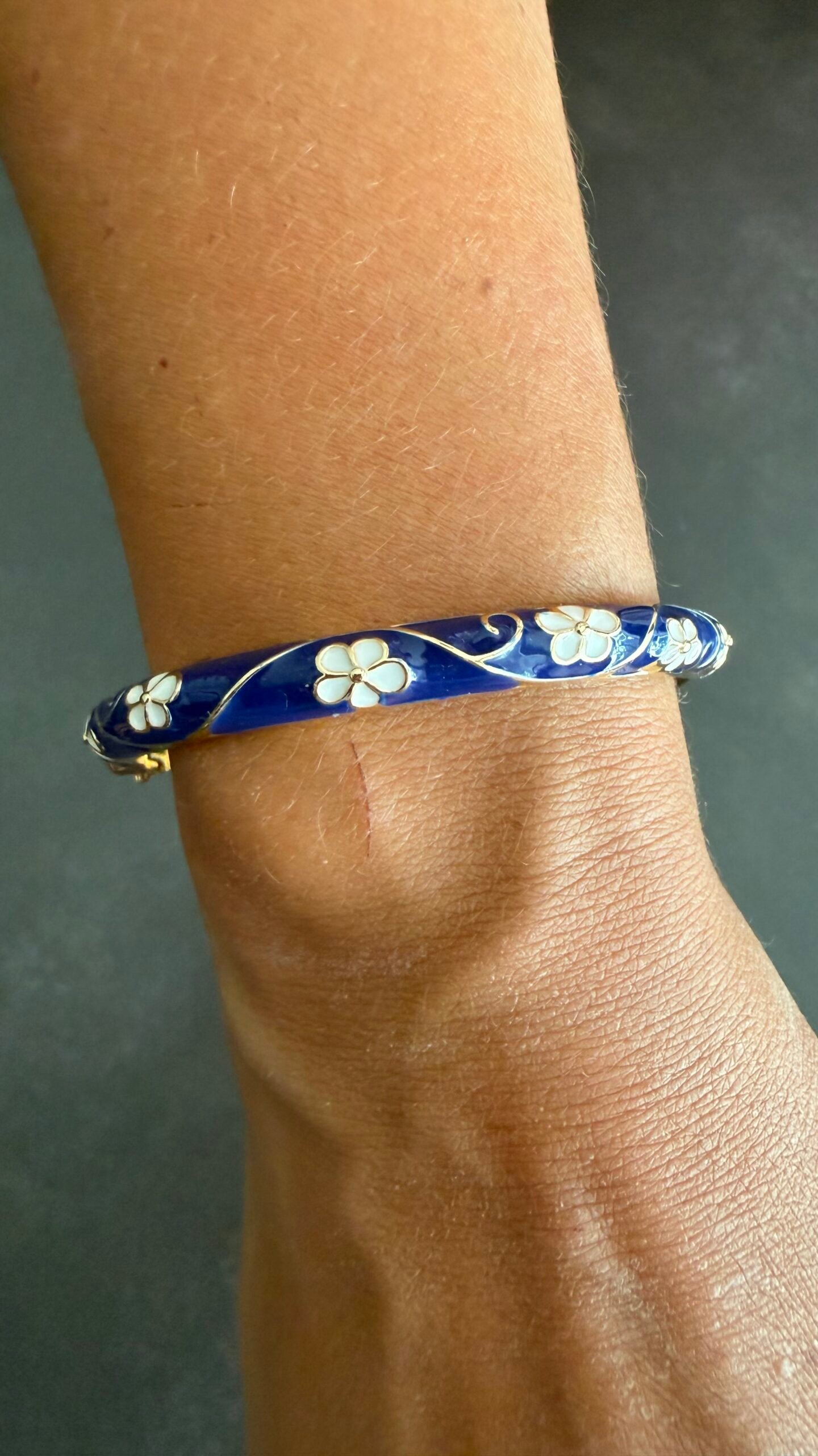 Bracelet Jonc Émaillé Bleu Marine Fleurs Blanches 2 Bracelet jonc émaillé bleu marine au poignet, fleurs blanches en émail et contours dorés