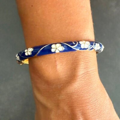 Bracelet jonc en laiton doré émaillé bleu marine à fleurs blanches porté au poignet