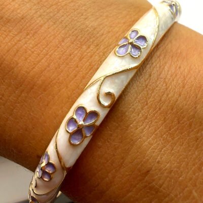 Bracelet jonc en laiton doré émaillé crème à fleurs mauves porté au poignet