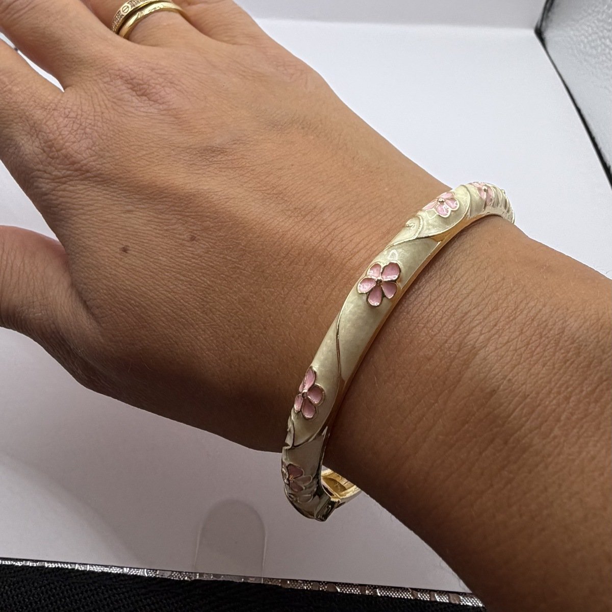 Bracelet Jonc Émaillé Fleurs Roses 4 Bracelet jonc émaillé crème à fleurs roses porté au poignet, laiton doré