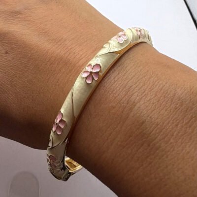 Bracelet jonc en laiton doré émaillé crème à fleurs roses porté au poignet