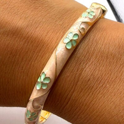 Bracelet jonc en laiton doré émaillé crème à fleurs vertes porté au poignet