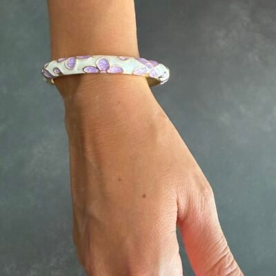 Main portant le bracelet jonc émaillé mauve à fleurs lilas, acier inoxydable doré