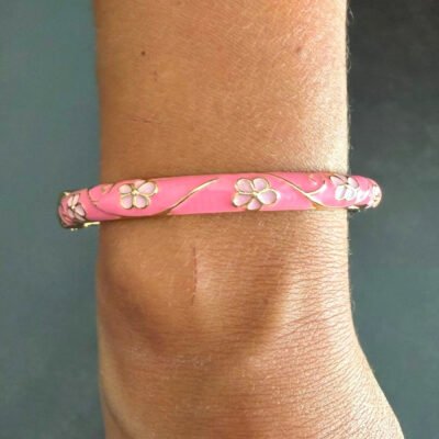Bracelet jonc en laiton doré émaillé rose à fleurs blanches porté au poignet