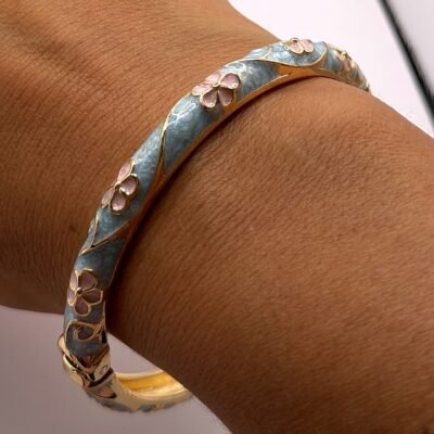 Bracelet jonc en laiton doré émaillé turquoise fleurs roses au poignet, vue rapprochée