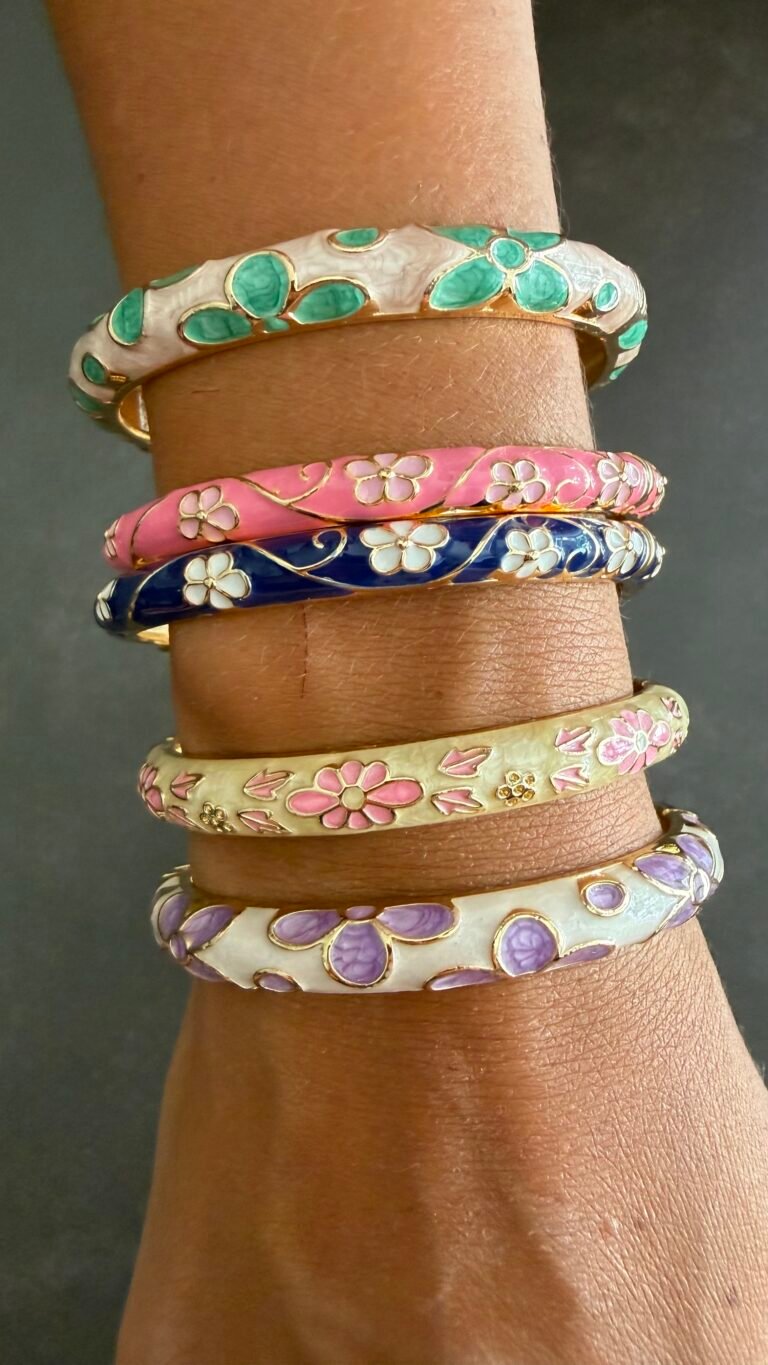 Cinq bracelets joncs émaillés empilés au poignet : vert d'eau, rose, bleu marine, ivoire et mauve