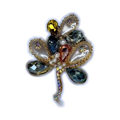Broche fleur à pétales de cristal et perles sur fond blanc