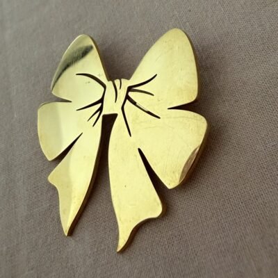 Broche nœud papillon dorée reflets métal poli Broche nœud papillon dorée vue de trois quarts, reflets sur le métal poli