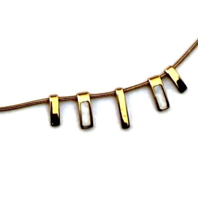 Gros plan sur les cinq barrettes dorées du collier, dont deux ajourées d'un insert blanc
