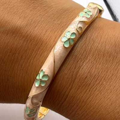Bracelet jonc émaillé crème à fleurs vert d’eau porté au poignet, gros plan sur l’émail en relief