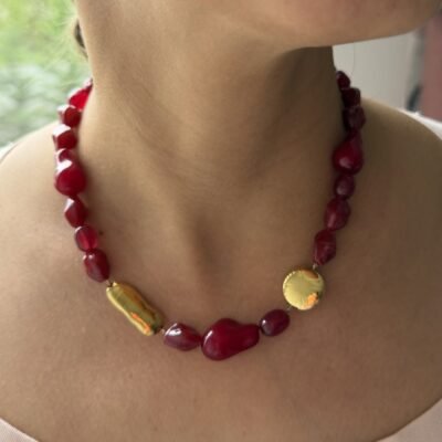 Collier pierre rouge doré porté au cou, perles rouges et deux pièces dorées