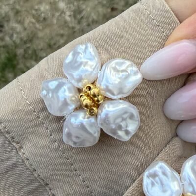 Gros plan sur le couvre-bouton fleur perles baroques, cinq pétales nacrés et pistil doré