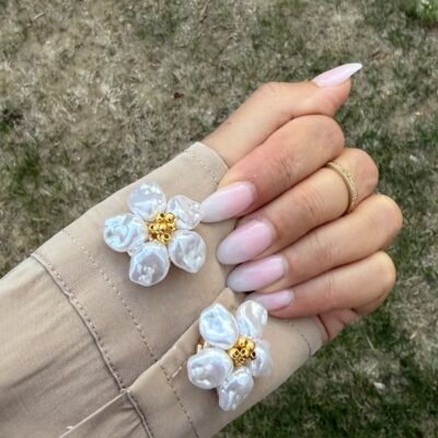 Paire de couvre-boutons fleur perles baroques portée sur les poignets d'une chemise beige