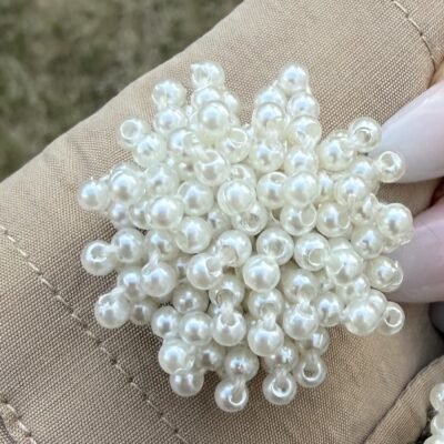 Gros plan sur le couvre-bouton perles nacrées, grappe de petites perles blanches
