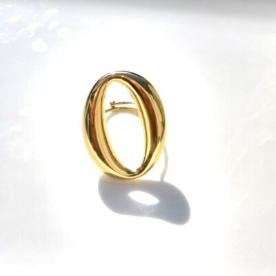 Bague grand ovale ajouré dorée posée sur un plateau blanc