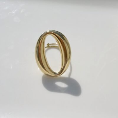 Bague grand ovale ajouré dorée posée sur un plateau blanc