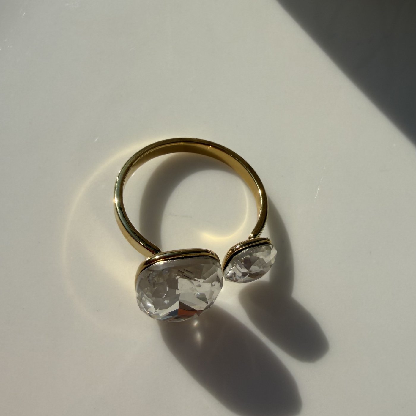 Bague Toi et Moi Cristaux Dorée 4 Bague ouverte dorée à deux cristaux posée sur un plateau blanc