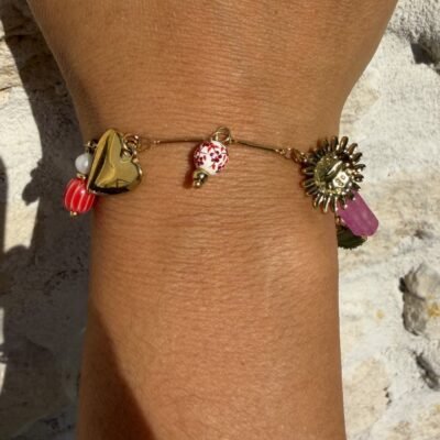 Bracelet breloques abeille porté au poignet, cœur doré, perle à fleurs rouges et soleil