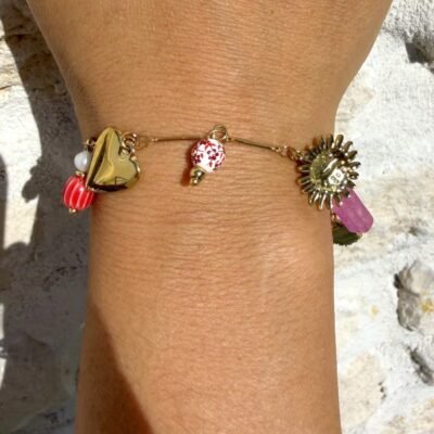 Bracelet breloques abeille porté au poignet, cœur doré, perle à fleurs rouges et soleil