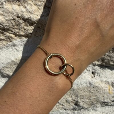 Bracelet double anneau entrelacé doré porté au poignet, gros plan