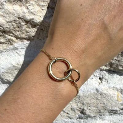 Bracelet double anneau entrelacé doré porté au poignet, gros plan