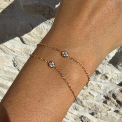 Bracelet double chaîne doré à deux solitaires porté au poignet