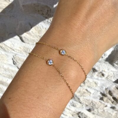 Bracelet double chaîne doré à deux solitaires porté au poignet