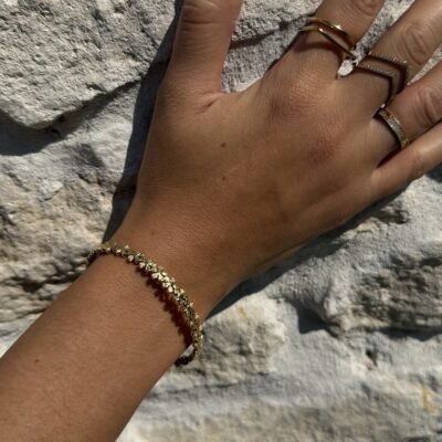 Bracelet fleurs doré porté avec des bagues dorées