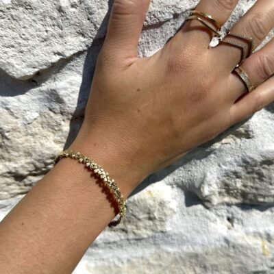 Bracelet fleurs doré porté avec des bagues dorées