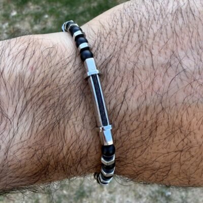 Bracelet homme perles noires et écrous acier porté au poignet, tube en acier poli