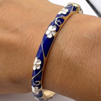 Bracelet jonc émaillé bleu marine à fleurs blanches porté au poignet