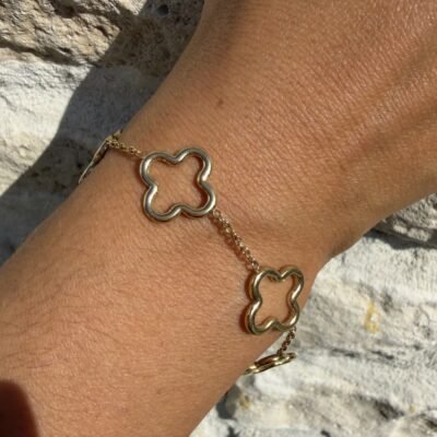 Bracelet multi-trèfles ajourés doré porté au poignet, gros plan