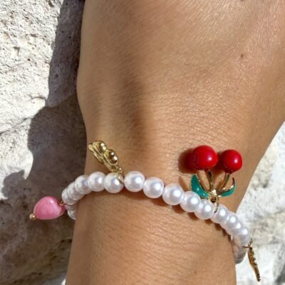 Bracelet de perles à breloques cerises porté au poignet, gros plan
