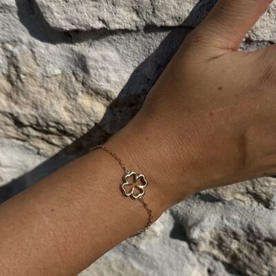 Bracelet trèfle ajouré doré porté avec des bagues dorées