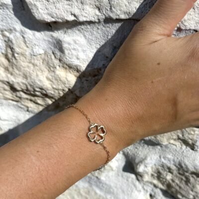 Bracelet trèfle ajouré doré porté avec des bagues dorées