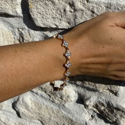 Bracelet trèfles dorés sertis de strass blancs porté au poignet