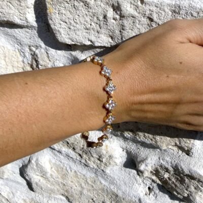 Bracelet trèfles dorés sertis de strass blancs porté au poignet