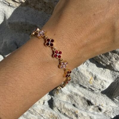 Gros plan sur le bracelet trèfles strass rouges et roses doré porté