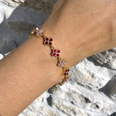 Gros plan sur le bracelet trèfles strass rouges et roses doré porté