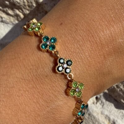 Bracelet trèfles dorés sertis de strass verts porté au poignet