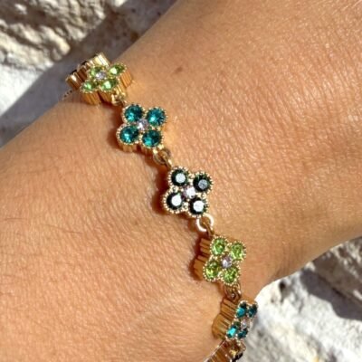 Bracelet trèfles dorés sertis de strass verts porté au poignet