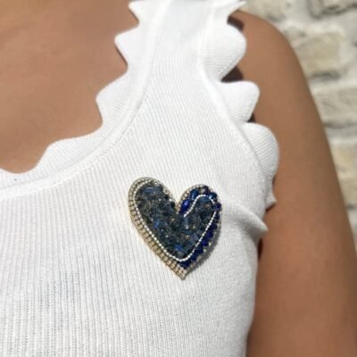 Broche cœur cristaux bleus portée sur un top blanc